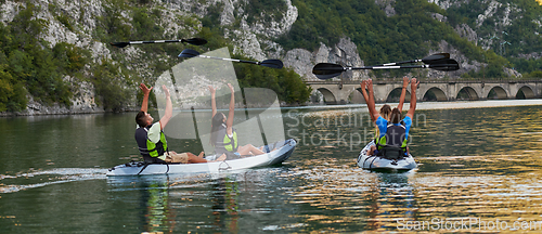 Image of A group of friends enjoying having fun and kayaking while exploring the calm river, surrounding forest and large natural river canyons