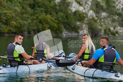 Image of A group of friends enjoying having fun and kayaking while exploring the calm river, surrounding forest and large natural river canyons