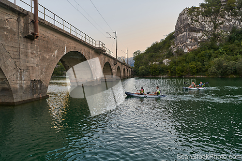 Image of A group of friends enjoying having fun and kayaking while exploring the calm river, surrounding forest and large natural river canyons