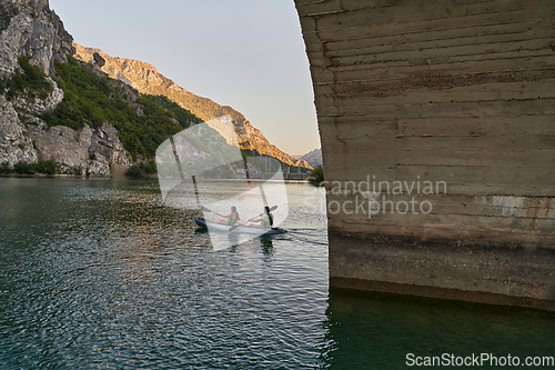 Image of A group of friends enjoying having fun and kayaking while exploring the calm river, surrounding forest and large natural river canyons