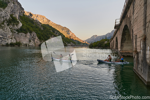 Image of A group of friends enjoying having fun and kayaking while exploring the calm river, surrounding forest and large natural river canyons