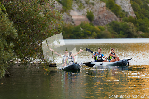 Image of A group of friends enjoying having fun and kayaking while exploring the calm river, surrounding forest and large natural river canyons