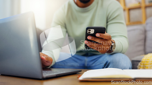 Image of Phone, laptop and man hands typing while doing research for a freelance project in his living room. Technology, keyboard and male freelancer working online with a computer and cellphone at his home.