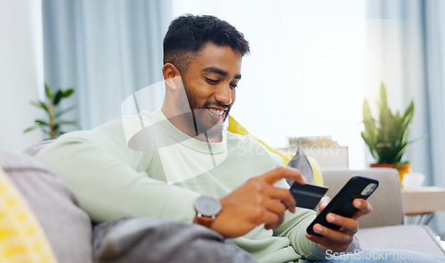 Image of Credit card, finance and man with smartphone for online shopping in lounge at home. Indian, visa and money for e commerce transaction and search the internet for investment or product.