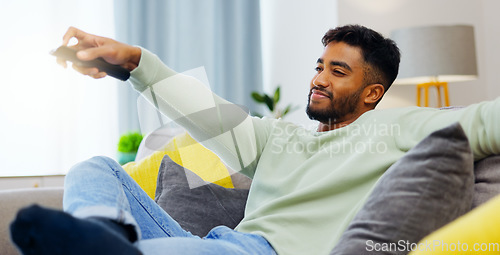 Image of Watching tv, relax man and happy on sofa, streaming movies and news on television in living room in house. Calm person in home with remote for subscription service online on the couch in apartment