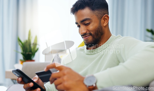 Image of Credit card, finance and man with smartphone for online shopping in lounge at home. Indian, visa and money for e commerce transaction and search the internet for investment or product.