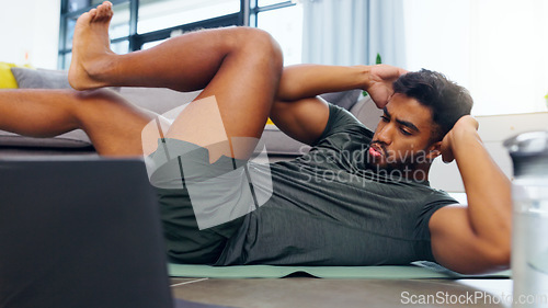 Image of Fitness man, home workout and laptop while watching online exercise tutorial in the living room at home. Fit and active man doing crunches for abs while using internet for a health and wellness blog