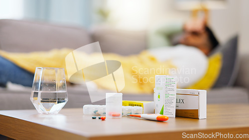 Image of Medicine, sick and man on the sofa with pills for an allergy, virus or cold. Healthcare, covid and African male on the couch with medication for a flu, disease or antibiotics for an illness