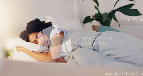 Image of Young black woman sleeping in bed in her bedroom while resting and having a dream at home. Relax, peaceful and calm African girl taking a nap with a comfortable pillow and blanket at her house.