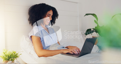 Image of Blog writer typing with laptop for internet streaming website and reading funny social media post in bed at home. Woman freelance worker in bedroom working remote while writing funny or comic web con