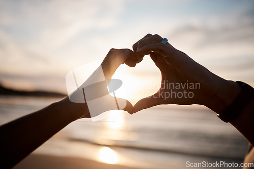 Image of Couple, heart and hands at beach in sunset for love, care and relax on holiday, vacation and travel. Closeup of people, silhouette and finger shape at sea for support, freedom and emoji sign in sky