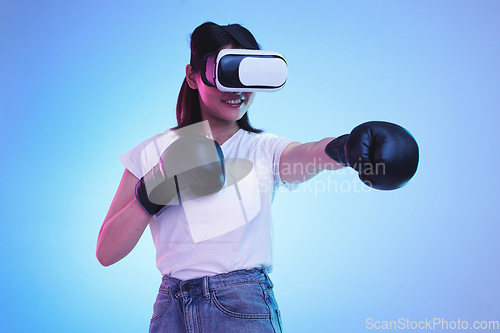 Image of AI, virtual reality and a gamer woman boxing on a blue background in studio for fitness or exercise. Metaverse, sports and training with a young female boxer playing an online fantasy game for health