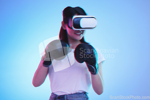 Image of Virtual reality, metaverse and a gamer woman boxing on a blue background in studio for fitness or exercise. AI, sports and training with a young female boxer playing an online fantasy game for health