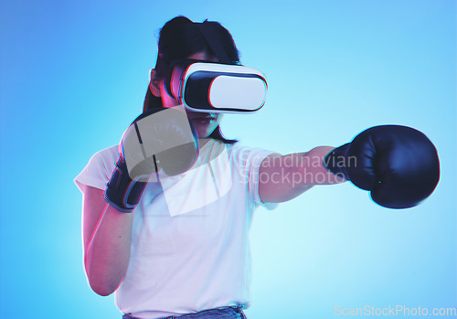 Image of AI, metaverse and a gamer woman boxing on a blue background in studio for fitness or exercise. Virtual reality, sports and training with a young female boxer playing an online fantasy game for health