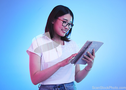 Image of Young woman, student and tablet for online education, e learning and study on blue, studio background. Happy person typing on digital technology, reading social media and school or youth information