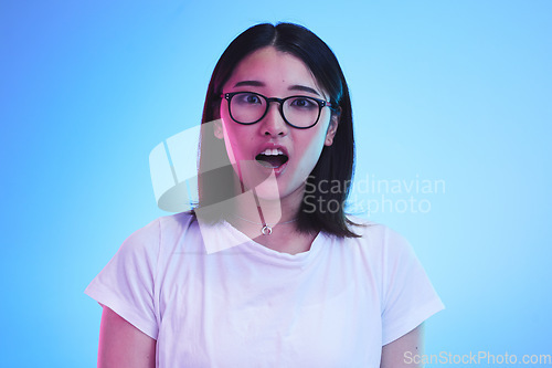 Image of Surprise, portrait and face of Asian woman with wow expression or open mouth for drama, deal and promotion. Omg, wtf and portrait of person with discount emoji isolated in a studio blue background