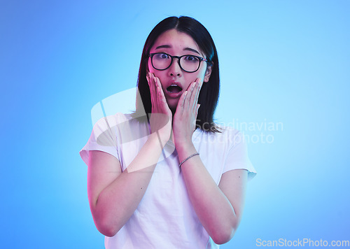 Image of Surprise, open mouth and face of Asian woman with wow expression or shocked for drama, deal and promotion. Omg, wtf and portrait of person with discount emoji isolated in a studio blue background