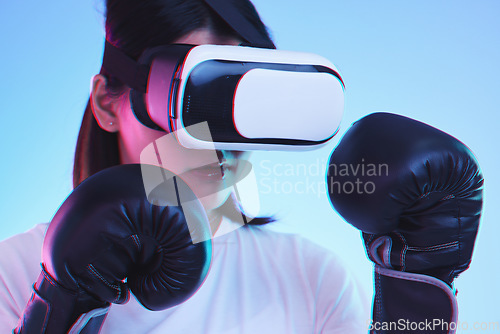 Image of Sports, metaverse and a gamer woman boxing on a blue background in studio for fitness or exercise. Virtual reality, ai and training with a young female boxer playing an online fantasy game for health