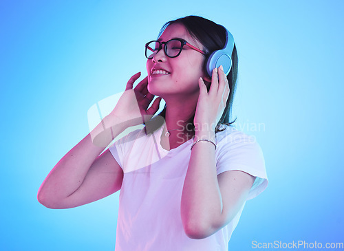 Image of Young woman, student and headphones for listening, audio streaming and happy subscription on blue background. Gen z, youth or person smile for mental health music or podcast on electronics in studio