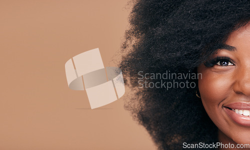 Image of Portrait, hair and mockup with a model black woman in studio on a brown background for natural cosmetics. Half face, smile and haircare with a happy afro female person on space for shampoo treatment