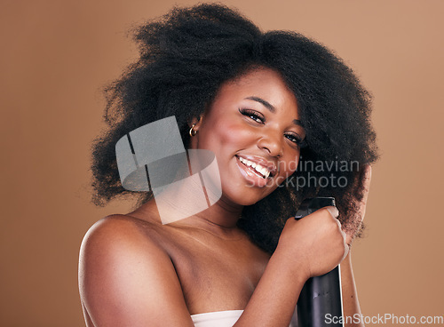 Image of Portrait, hair and spray with a model black woman in studio on a brown background for natural cosmetics. Face, keratin and haircare with a happy young afro female person indoor for shampoo treatment
