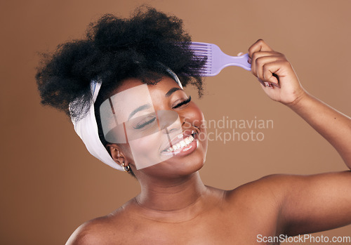 Image of Comb, hair care or happy black woman with afro, self love or smile on a brown studio background. Hairstyle, healthy growth or African model with natural shine or beauty with aesthetic or wellness