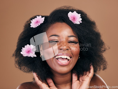 Image of Portrait, hair care or happy black woman with flowers, afro or smile on a brown studio background. Hairstyle, beauty and African model with texture, shine and volume with aesthetic, wellness and glow