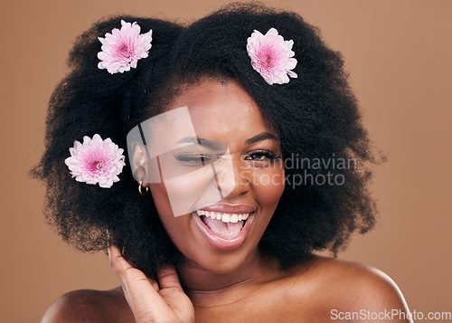 Image of Flowers, face wink and black woman in afro hair care, excited and beauty in studio isolated on a brown background. Portrait, floral hairstyle cosmetic and natural African model flirt in organic salon