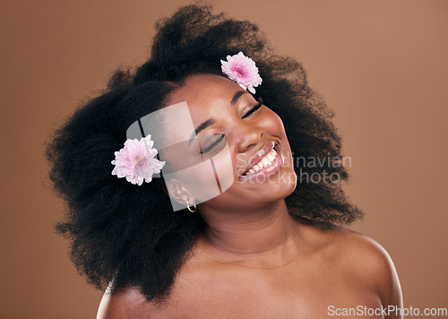 Image of Hair care, flowers and black woman, happy and beauty in studio isolated on a brown background. Smile, floral afro cosmetics or natural African model in organic salon treatment, wellness and hairstyle