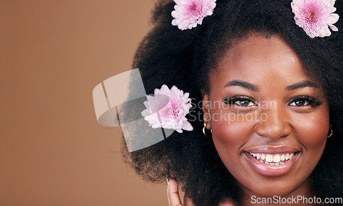 Image of Flowers, face and black woman in afro hair care, smile and beauty in studio isolated on a brown background mockup space. Portrait, floral hairstyle cosmetic and natural African model in organic salon