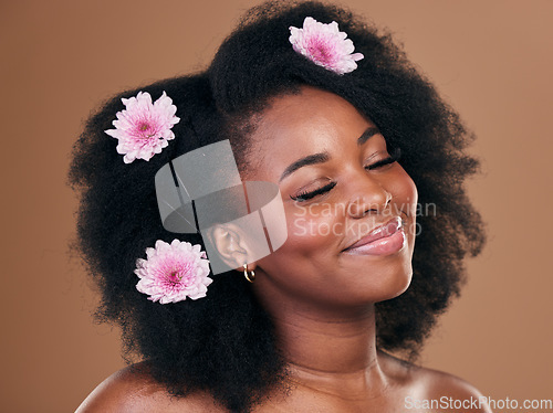 Image of Hair care, flowers and black woman, happy and beauty in studio isolated on a brown background. Smile, floral afro cosmetics or natural African model in organic salon treatment, wellness and hairstyle