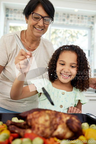 Image of Kitchen, food and a grandmother cooking with her grandchild in their home together for thanksgiving. Children, love and a roast with a senior woman preparing a meal with a girl for healthy nutrition