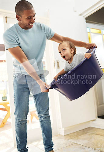 Image of Child, father and playing in laundry basket at home for family fun and housework or cleaning. A man laughing and swinging a funny toddler kid while together for bonding, game and development at house