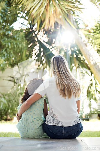 Image of Child, adoption and together with mom for hug, support or love in backyard, garden or family home of girl in foster care. Interracial, mother and daughter bonding in embrace or sitting outdoor