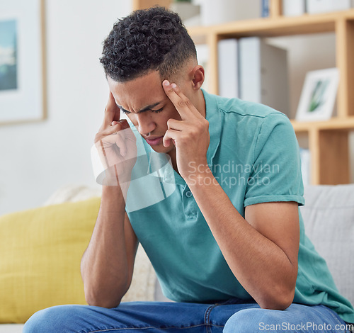 Image of Stress, home, and man on a couch, headache and burnout with pain, fatigue and mental health. Person, student or guy on a sofa, migraine or exhausted with anxiety, frustrated or depression in a lounge