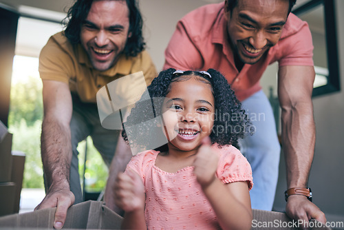 Image of Family home, girl and box with parents, push and gay dad with games, portrait and playing on floor with moving. LGBTQ men, female kid and cardboard package for car, airplane and driving in new house