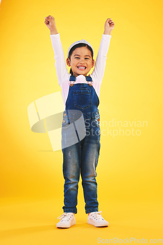 Image of Portrait, children and a winner girl on a yellow background in celebration of success or victory. Kids, goals and motivation with a young child cheering for an award or achievement in studio