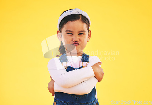 Image of Portrait, arms crossed and angry girl child in studio with bad, attitude or behavior problem on yellow background. Frown, face and asian kid with body language for no, frustrated or tantrum emoji