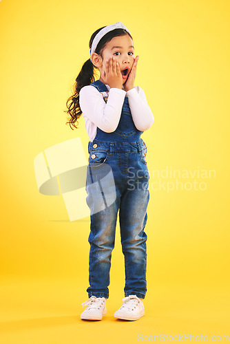 Image of Children, fashion and hands on face of girl child in studio with deal, sale or giveaway promo on yellow background. Wow, surprise and open mouth kid with emoji for news, announcement or sign up info