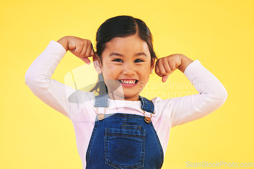 Image of Happy, portrait and girl child with arm flex in studio for confidence, strong and power on yellow background. Face, smile excited kid with bicep strength, pose and empowered, positive and growth sign