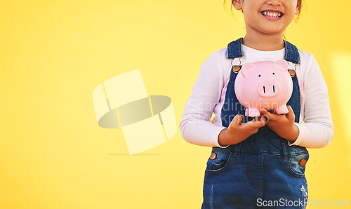 Image of Girl kid, piggy bank and saving in studio with smile, mockup space and excited by yellow background. Young female child, money box and start investment for promo, financial knowledge or future goal