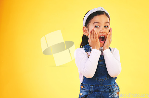 Image of Fashion, surprise and hands on face of girl child in studio wow, omg or wtf for promo, deal or giveaway on yellow background. Portrait, emoji and kid with open mouth for news, info or clothes sale