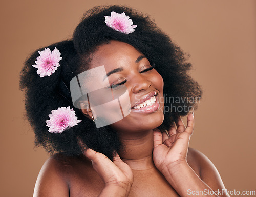 Image of Afro, hair or happy black woman with flowers, beauty care or smile on a brown studio background. Hairstyle, floral or natural African female model with shine or growth with volume, wellness or glow