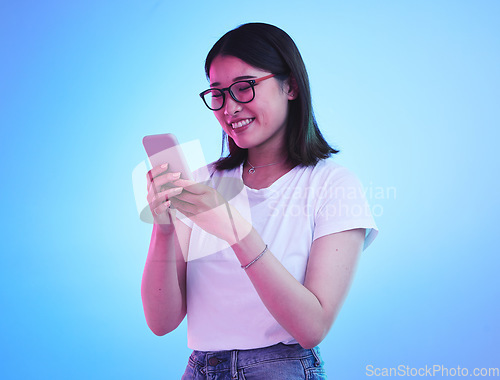 Image of Phone, typing an Asian woman on social media with mobile app, internet or web isolated in a studio blue background. Connection, cellphone and young female chatting with smile for communication