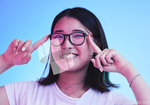 Image of Portrait, smile and woman with glasses on blue background in studio for optometry style. Happy asian model, gen z girl and face with spectacles for fashion, eye care and lens choice of cool frames