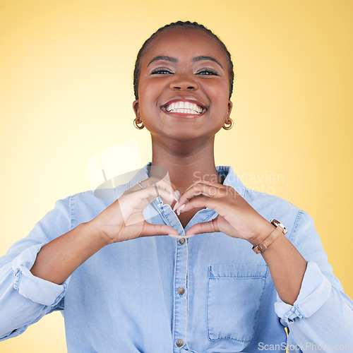 Image of Black woman, heart hands and health with emoji, smile in portrait and love isolated on yellow background. Support, care and kindness with respect, happiness and wellness, romance sign in a studio