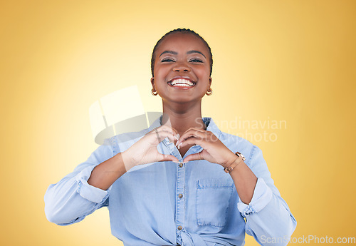 Image of Portrait, heart hands and black woman, smile and studio isolated on yellow background. Face, love sign and happy African person in kindness, care and empathy, support and trust, romance or solidarity