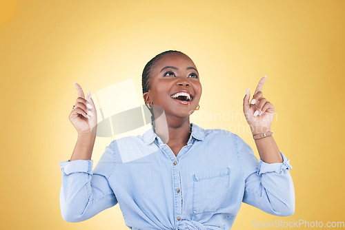 Image of Black woman, excited and surprise, pointing up and advertising with presentation news isolated on yellow background. Announcement, opportunity and offer with wow, communication and ads in studio