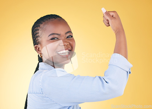 Image of Portrait, black woman and flex for power, smile and challenge on a yellow studio background. Face, happy person and model with strength, arm muscle and achievement with success, confident and winning