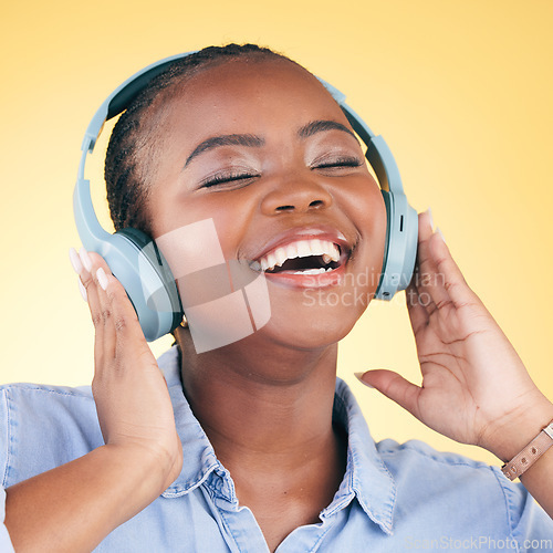 Image of Singing, music and black woman on headphones, smile and listening in studio isolated on a yellow background. Happy, radio and African person streaming podcast, audio and sound, hearing and freedom.